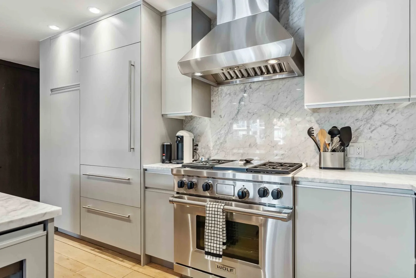 Una cocina moderna con una estufa de acero inoxidable bajo una campana metálica.