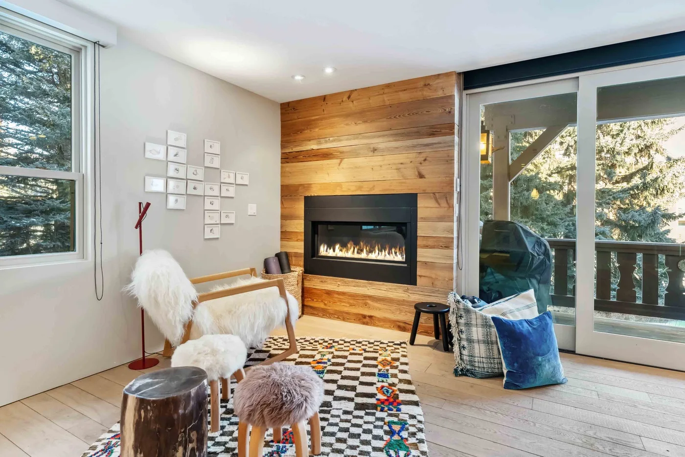 Una sala luminosa tiene una chimenea empotrada en una pared revestida de madera.