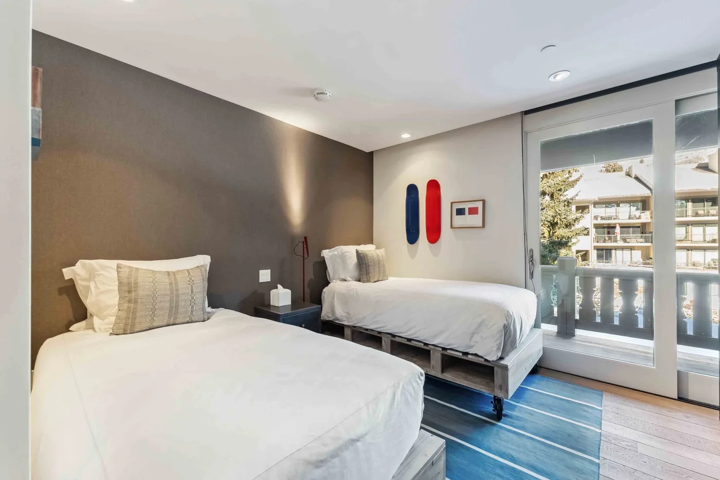 Un dormitorio con dos camas, suelo azul y una ventana grande.