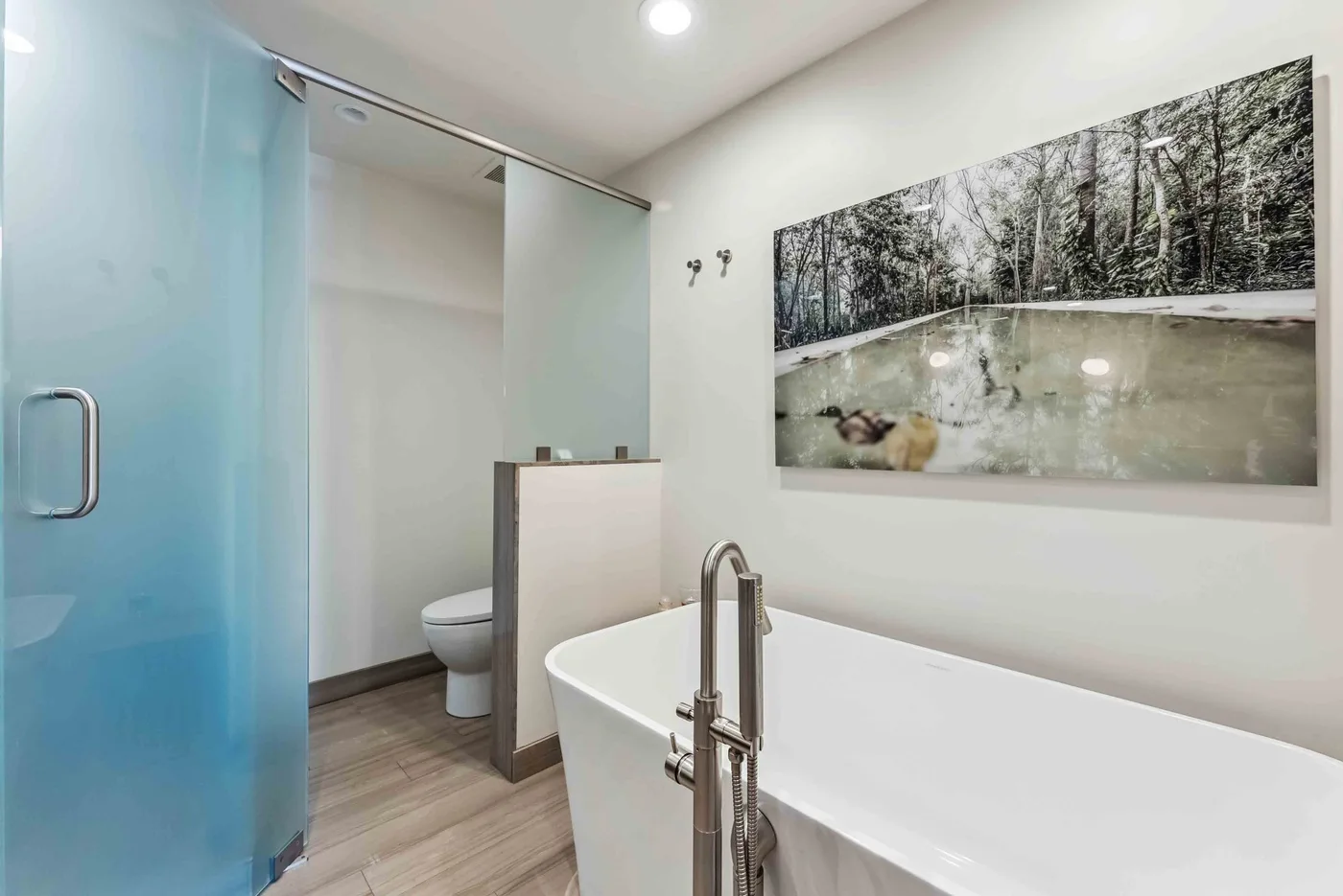 Un baño con bañera, ducha y arte enmarcado en la pared.