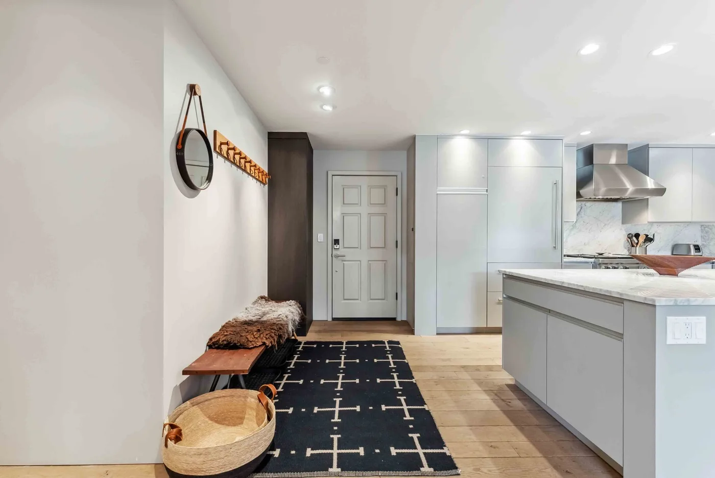 Una cocina luminosa con zona de entrada, isla central y alfombra estampada.