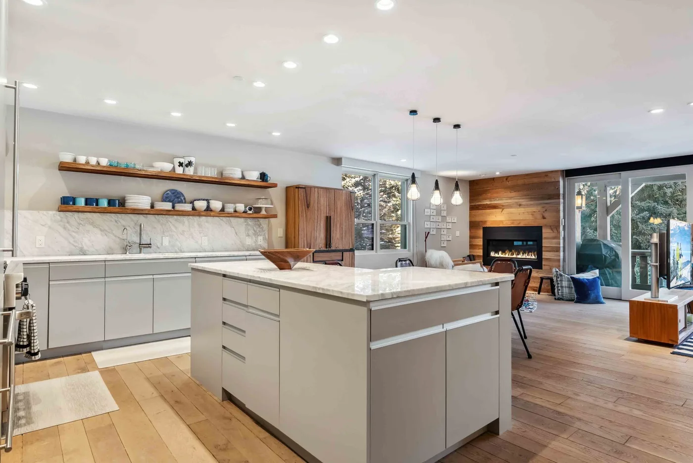 Una luminosa cocina abierta al salón, con una isla grande y una chimenea.