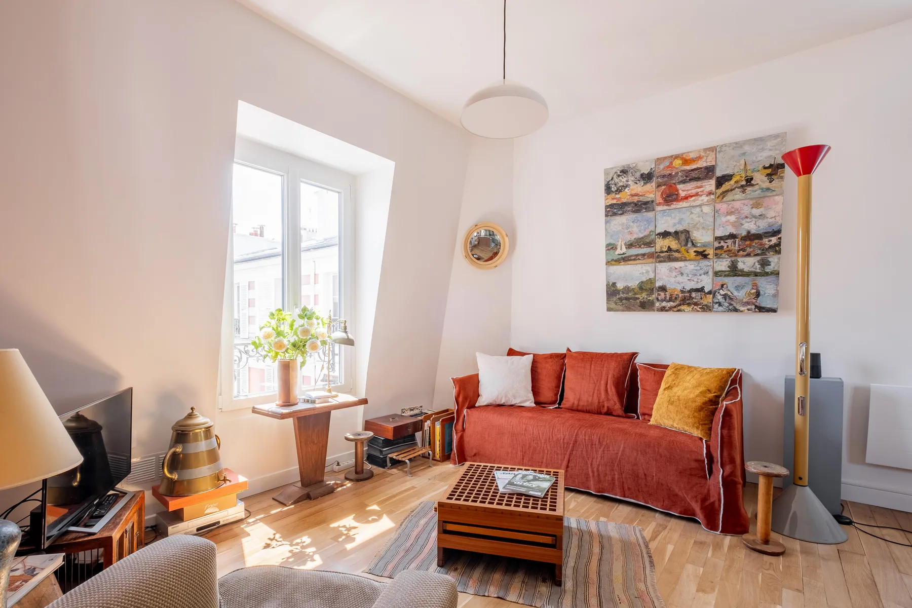 Una sala luminosa con asientos rojos, una mesa baja y una ventana grande.