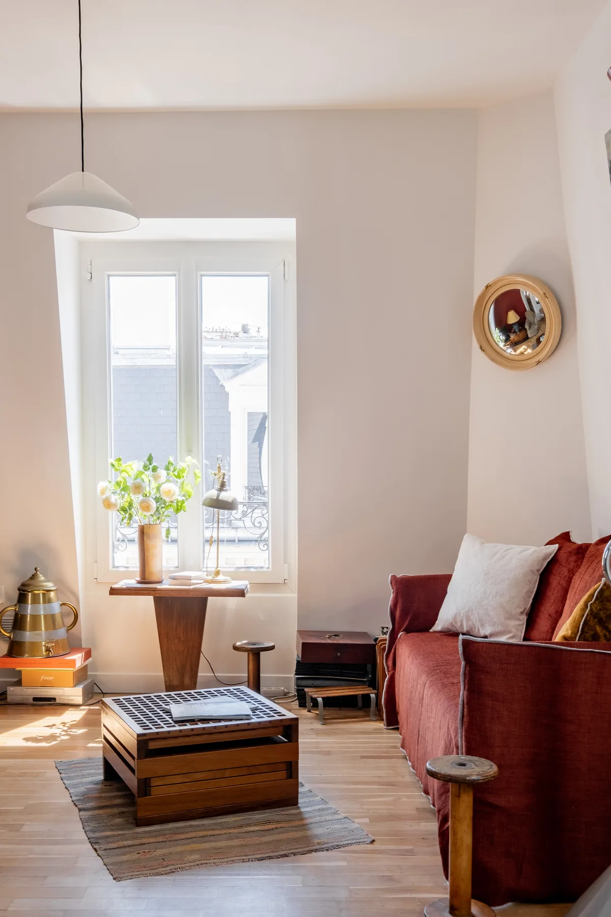 Una sala luminosa con un sofá rojo junto a una ventana soleada.