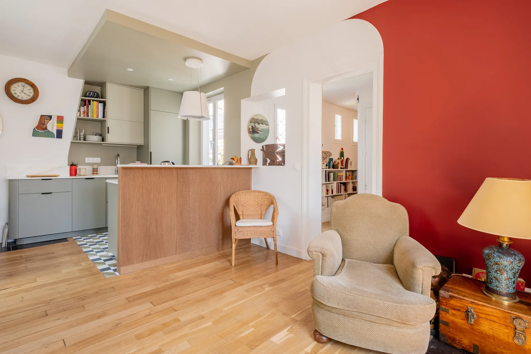 Un espacio de sala y cocina abierta con una barra y asientos junto a una pared roja.