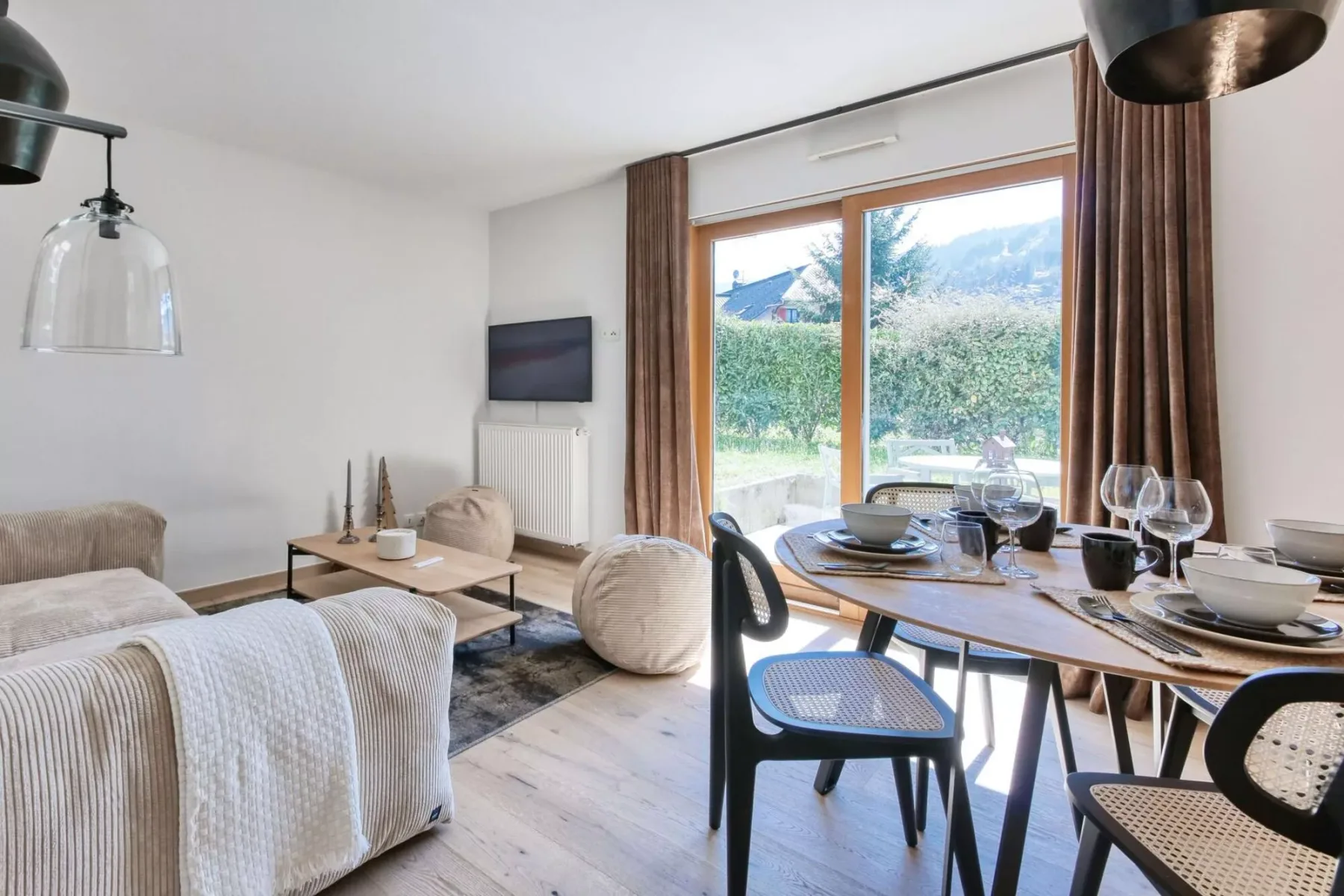 A bright living and dining area with a table beside large windows.