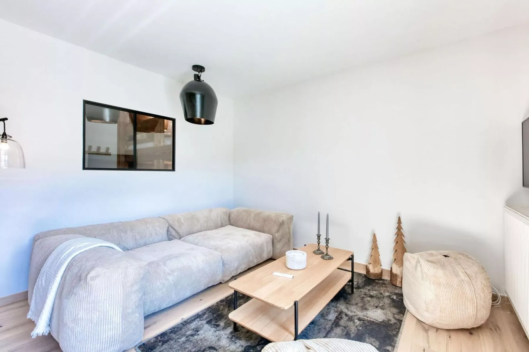 A bright living room with seating, a low table, and a patterned rug.