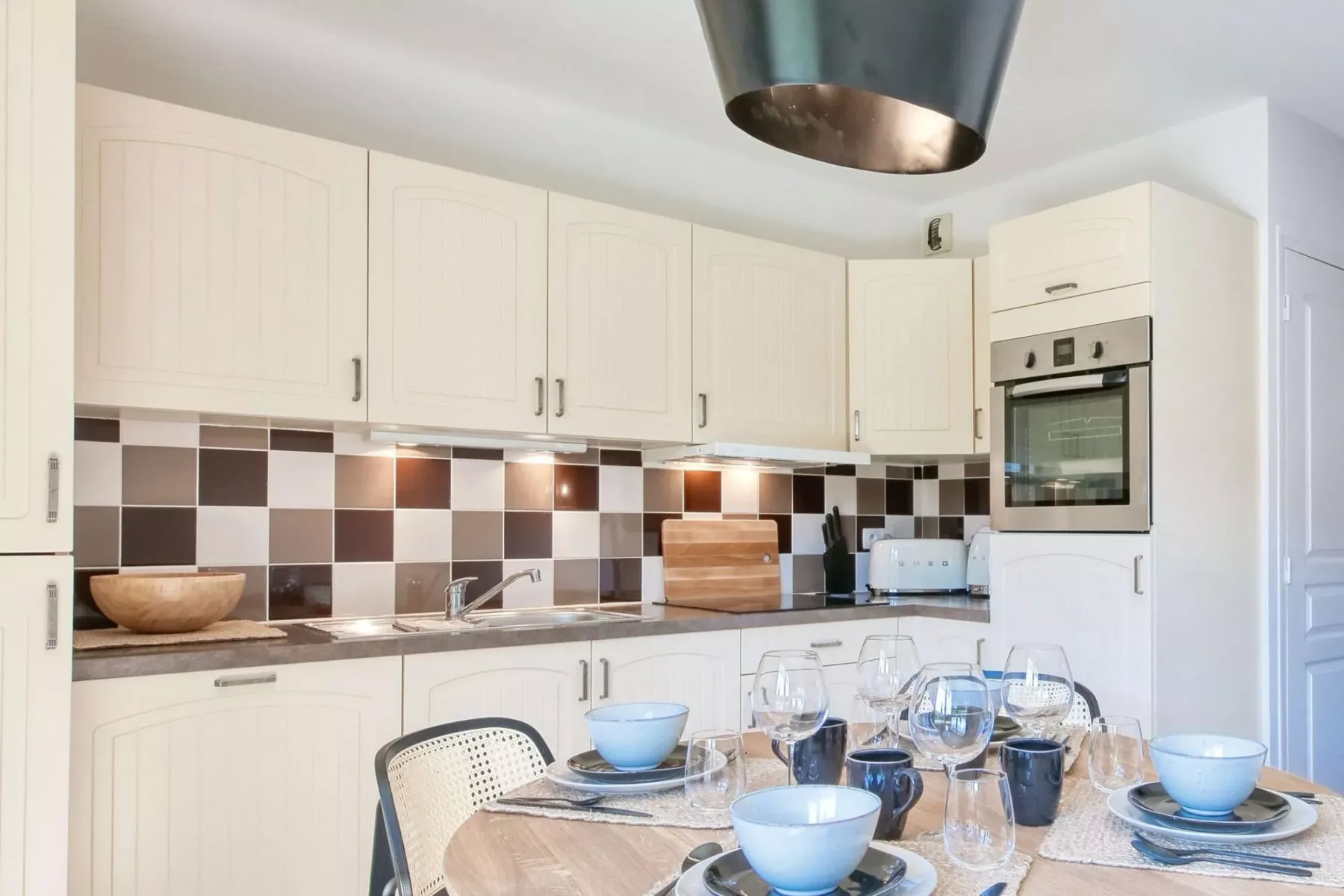 A bright kitchen with white cabinets and a dining table set with dishes.