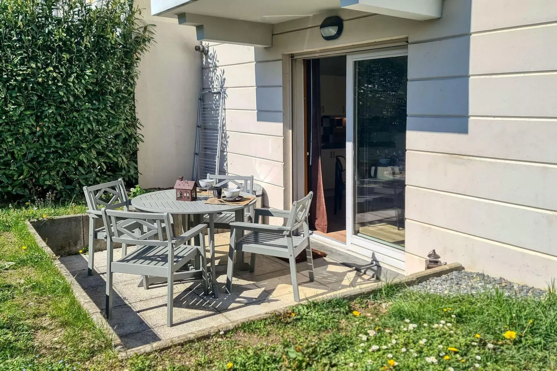 A small patio with outdoor seating and a table beside an open sliding glass door.