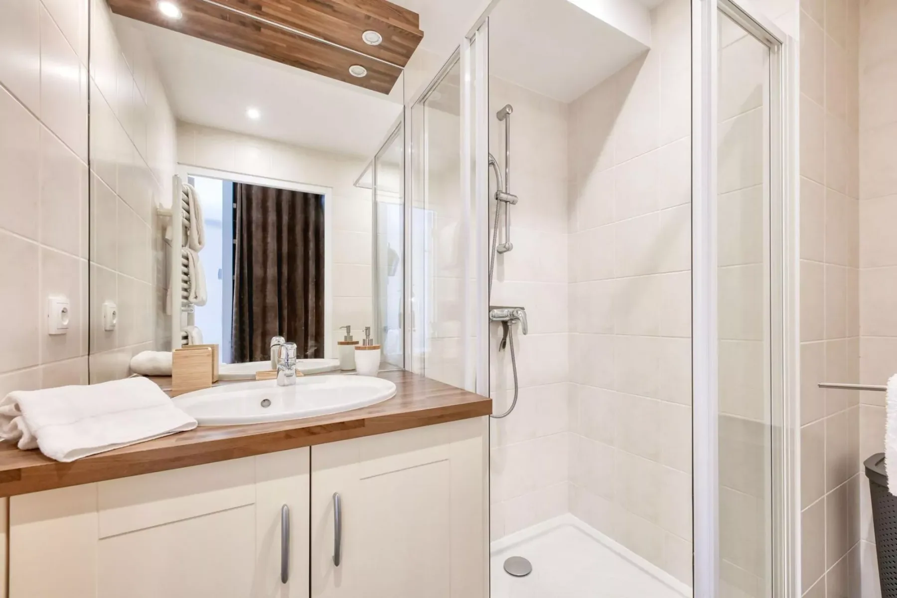 A bright bathroom with a vanity, sink, and glass-enclosed shower.