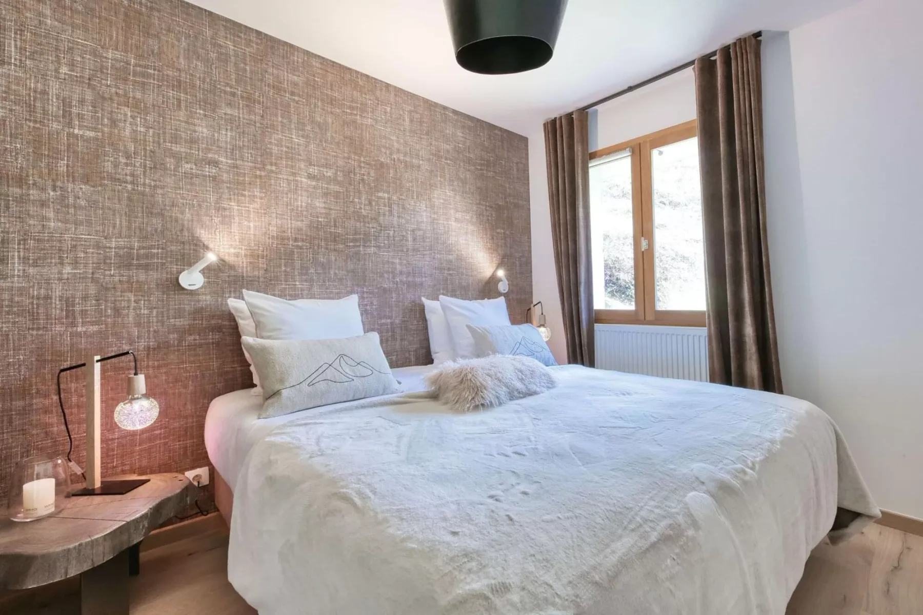 A bedroom with a large bed beside a window with curtains.