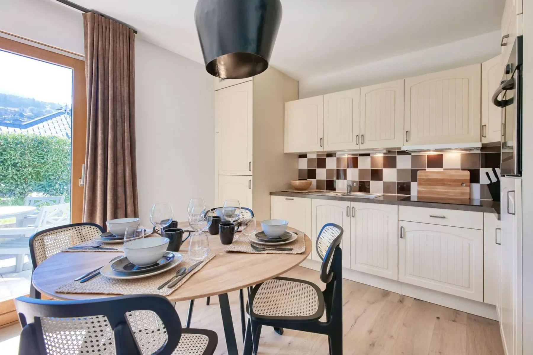 A dining area with a set table beside a bright kitchen.