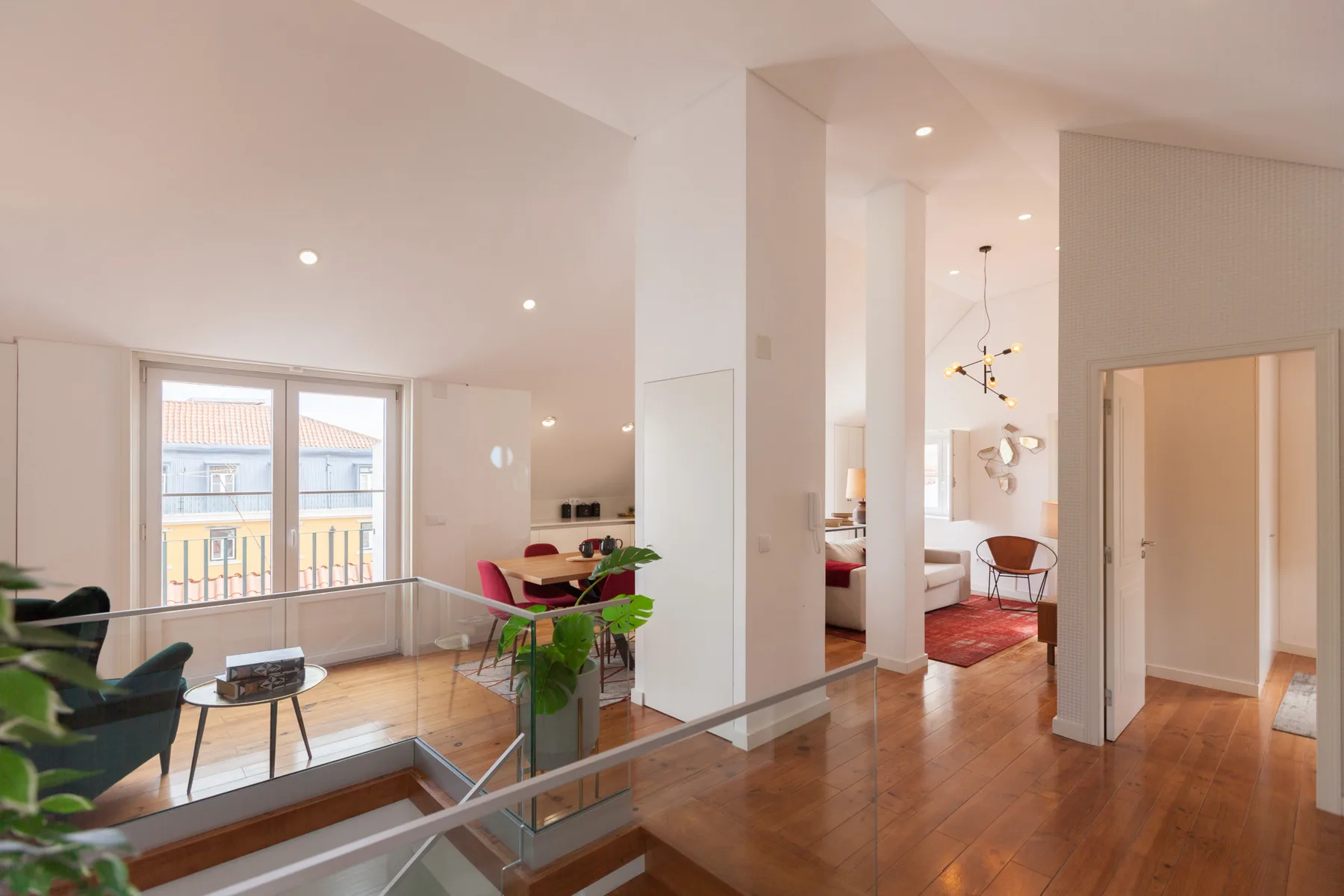 A bright open-plan living and dining area with a glass railing and large windows.