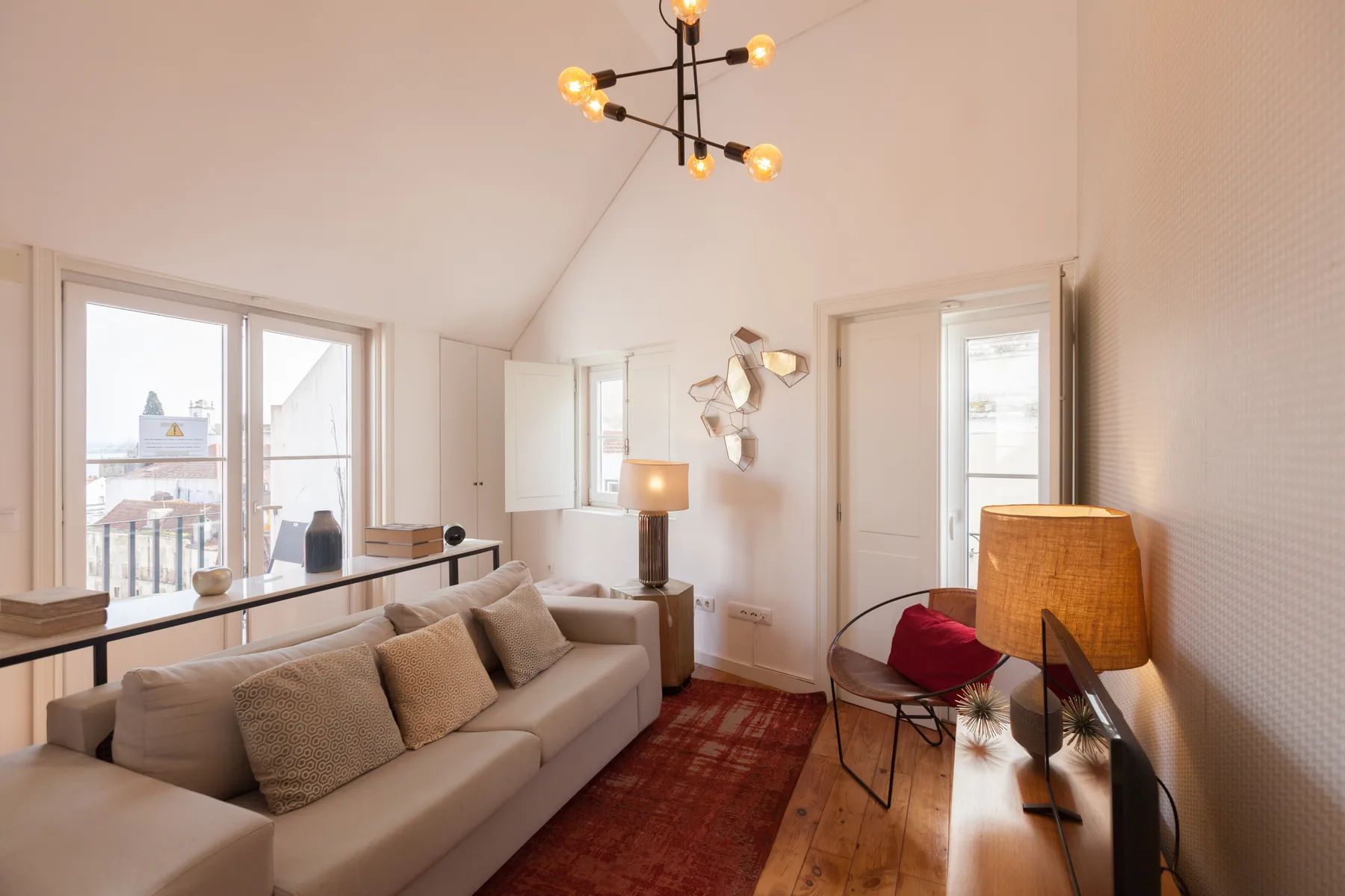 A bright living room with seating, a rug, and windows.