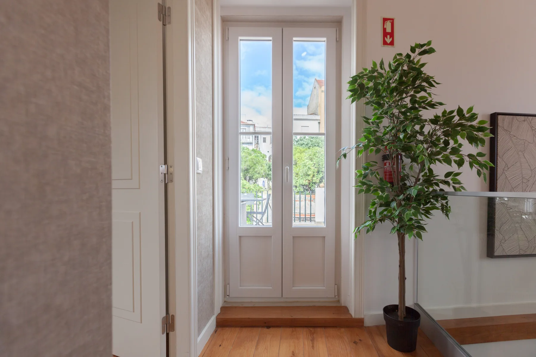 A bright interior entryway with glazed doors opening onto a small balcony.