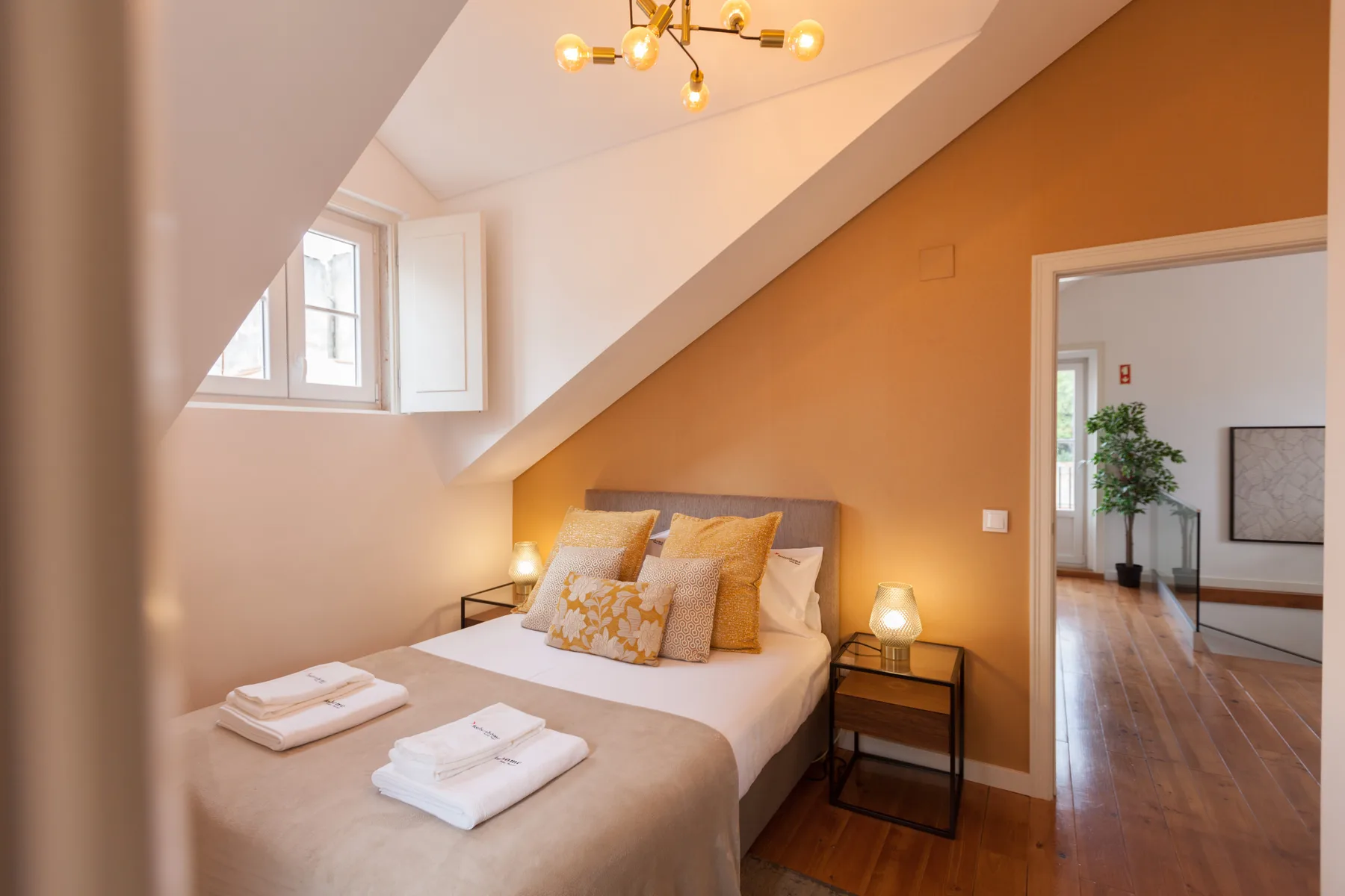 A bedroom with a bed beneath a sloped ceiling and a small window.
