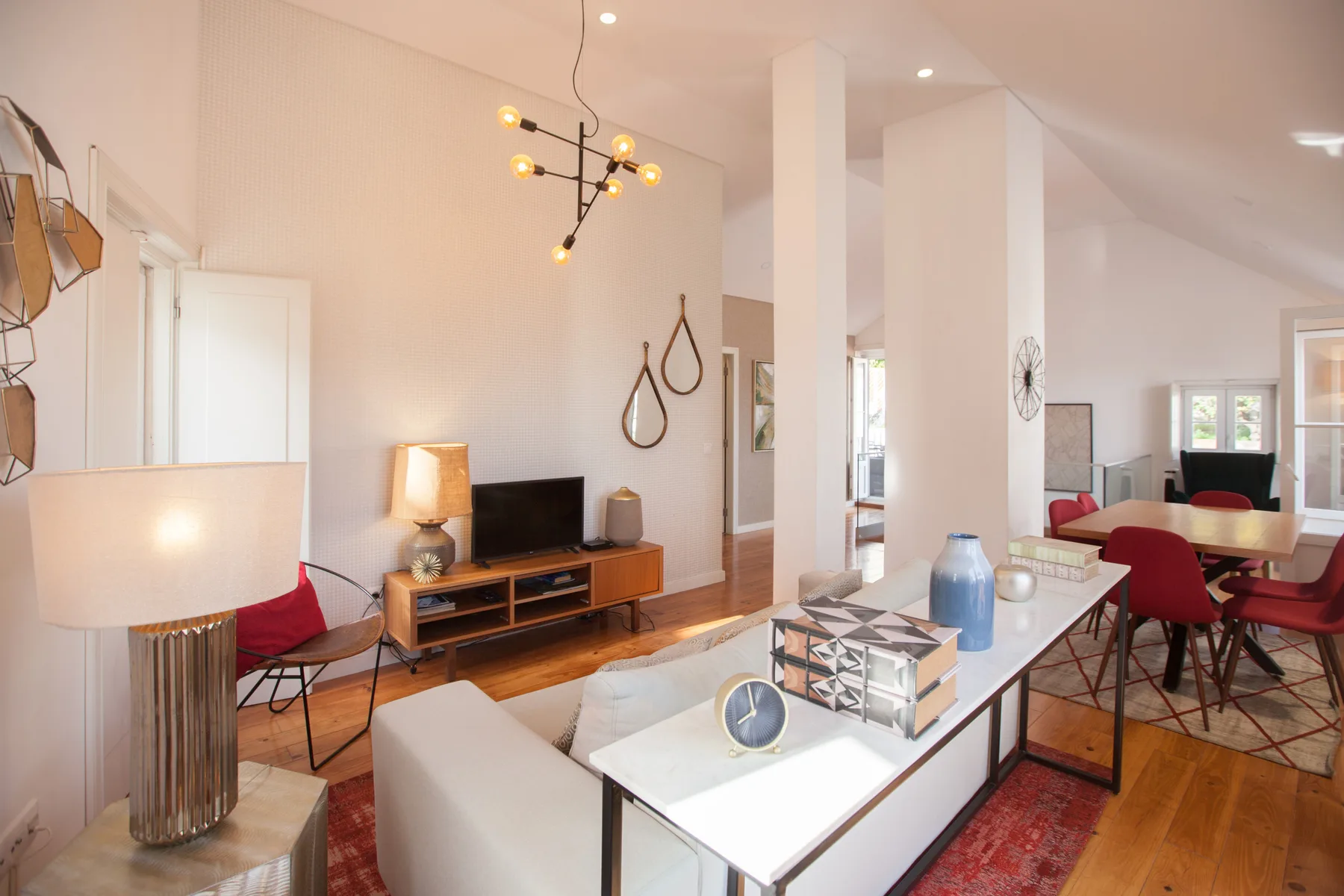 A bright living and dining area with a long table and red seating.