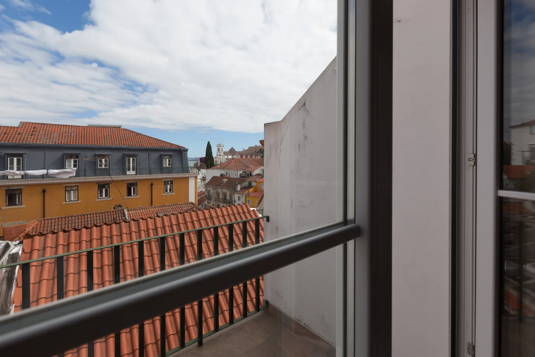 A balcony overlooks red-tiled rooftops and neighboring buildings.