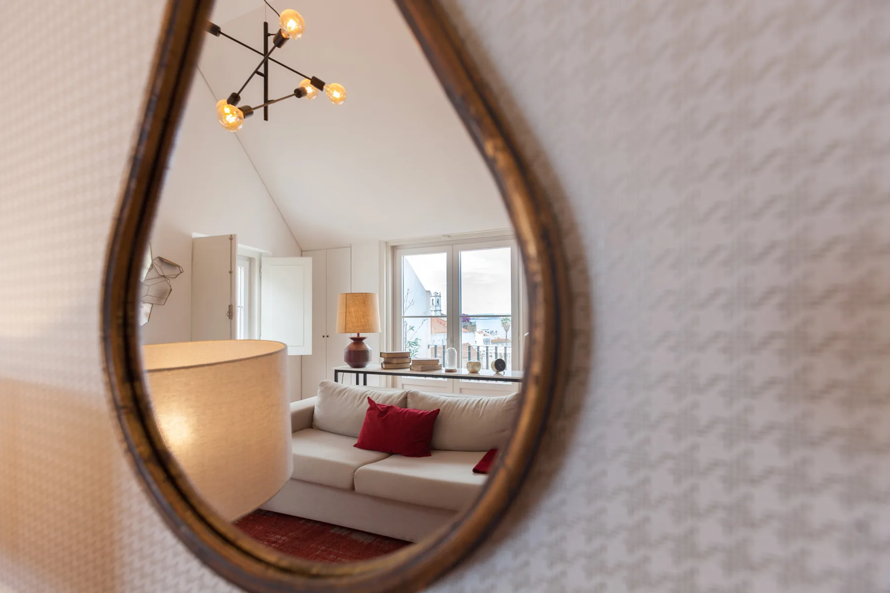 Living room with seating and a window, viewed through a wall mirror.