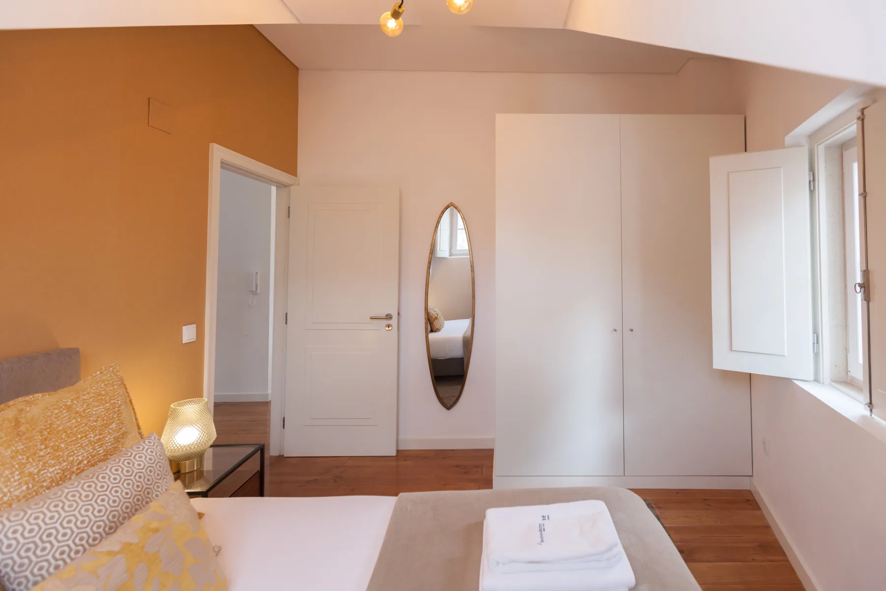 A bedroom with a bed, folded towels, and an open window.