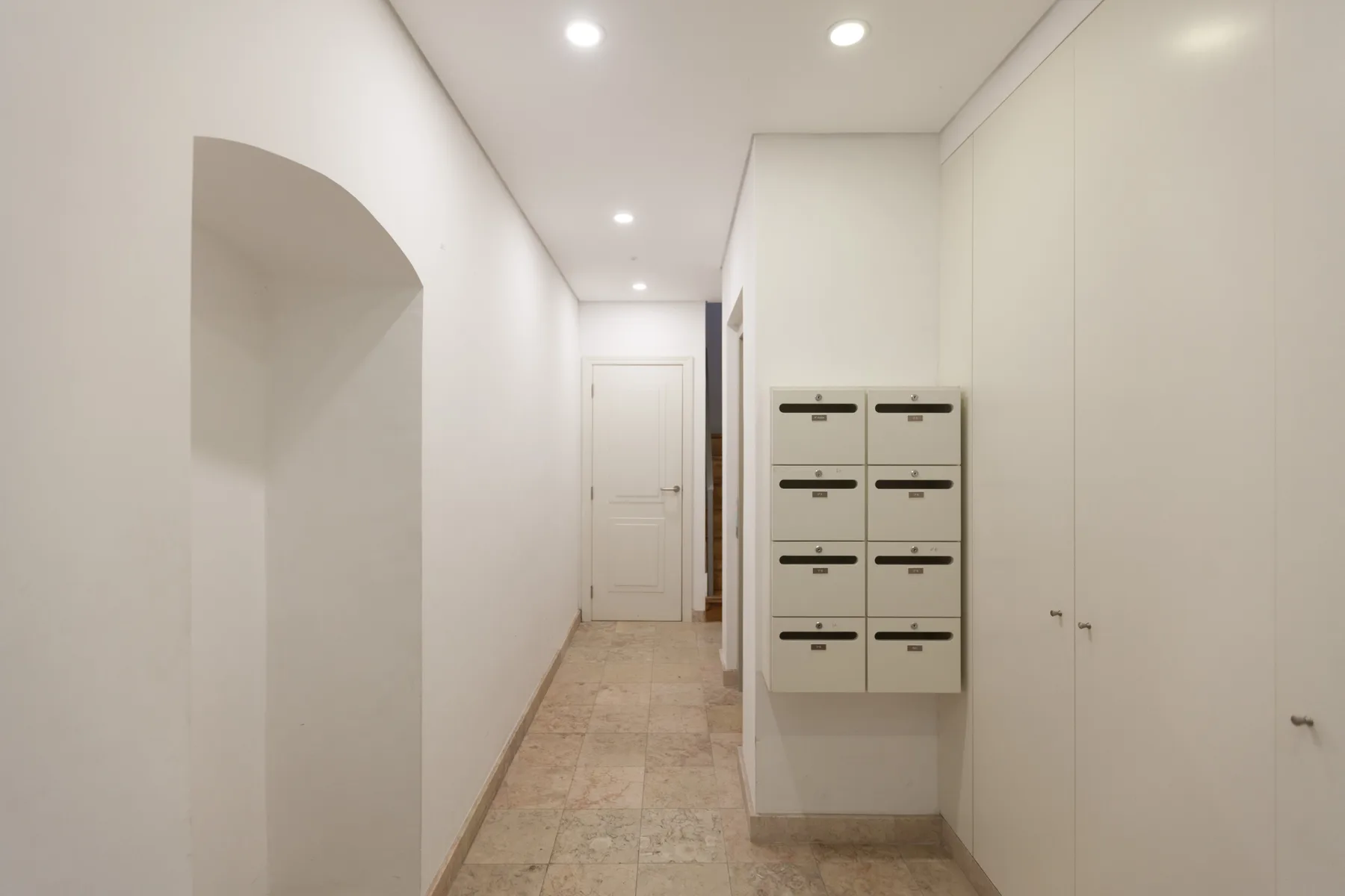 A bright interior hallway with a row of mailboxes along the wall.