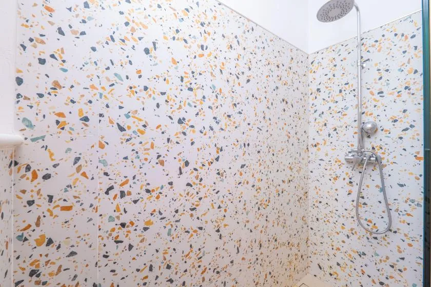 A tiled shower area with a wall-mounted showerhead and patterned walls.