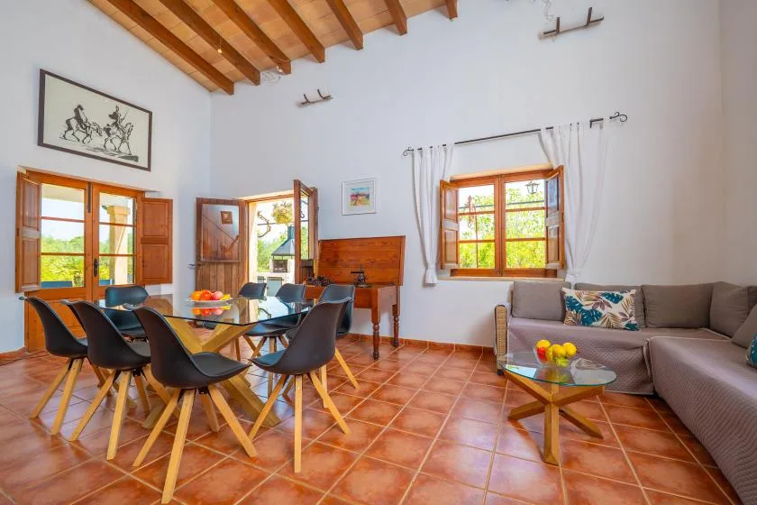 A bright living and dining room with a wooden dining table and a seating area.