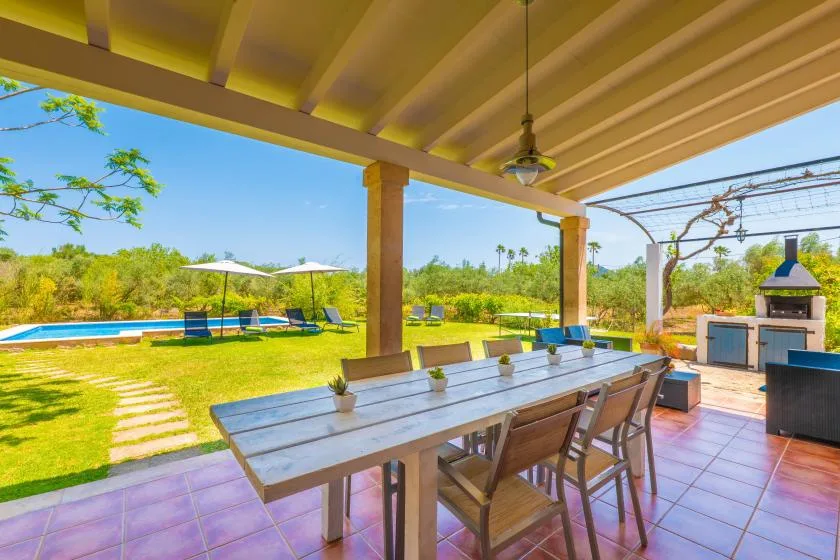 A covered outdoor dining area overlooks a pool and garden.