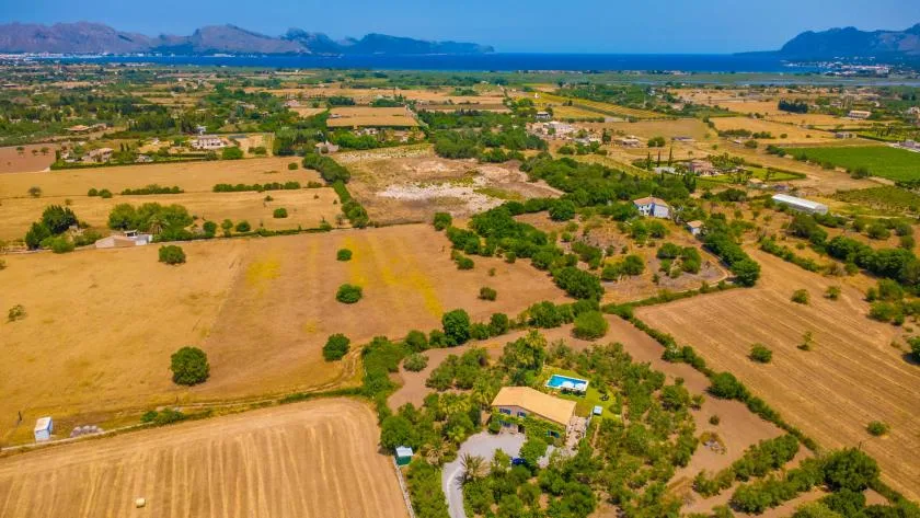 Aerial view of cultivated fields and scattered homes beneath distant hills.