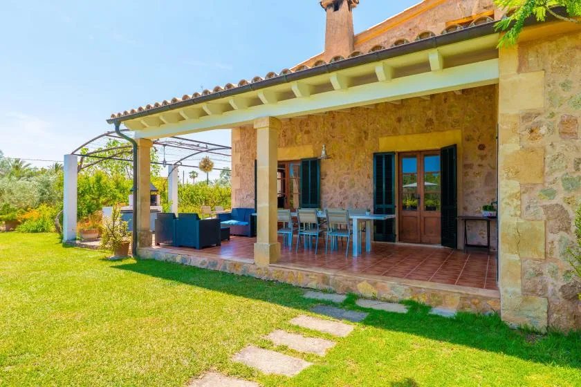 A covered outdoor patio with seating and a grassy lawn in front.