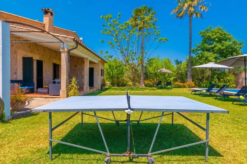 A garden patio with a ping-pong table on the lawn beside the house.