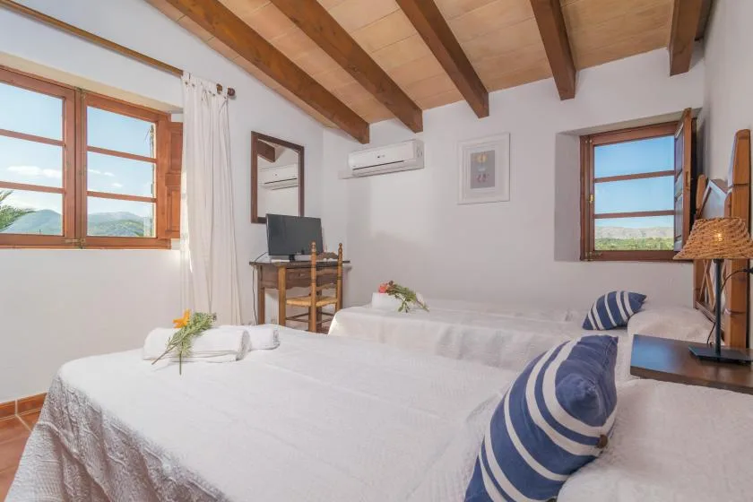 A bright bedroom with white bedding and exposed wooden ceiling beams.