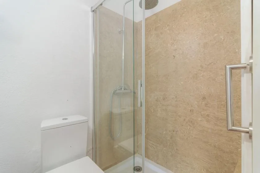 A bathroom with a glass-enclosed shower and toilet.