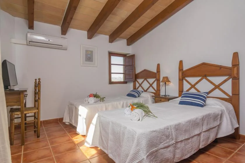 A bedroom with two beds, a wooden ceiling, and a window.
