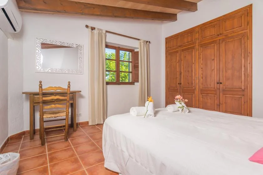 A bedroom with a large bed, wooden wardrobes, and a window with curtains.