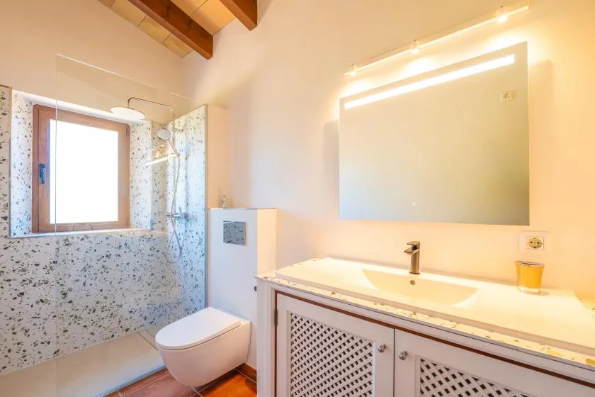 A bright bathroom with a sink, mirror, and shower.