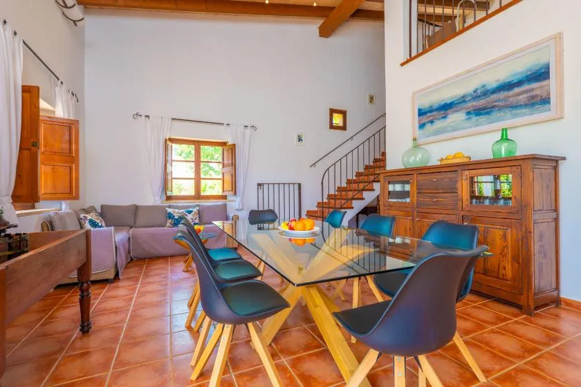 A dining area with a glass table and seating beside a living area.