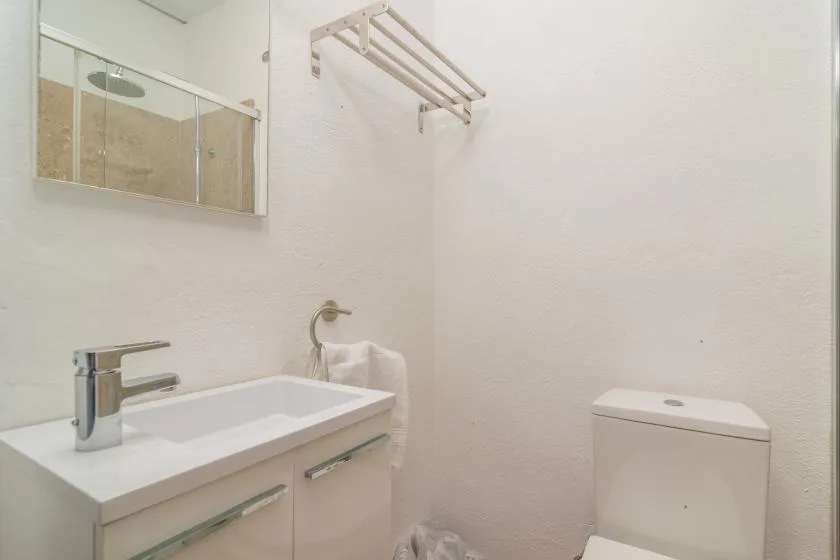 A bright bathroom with a sink, mirror, and toilet.