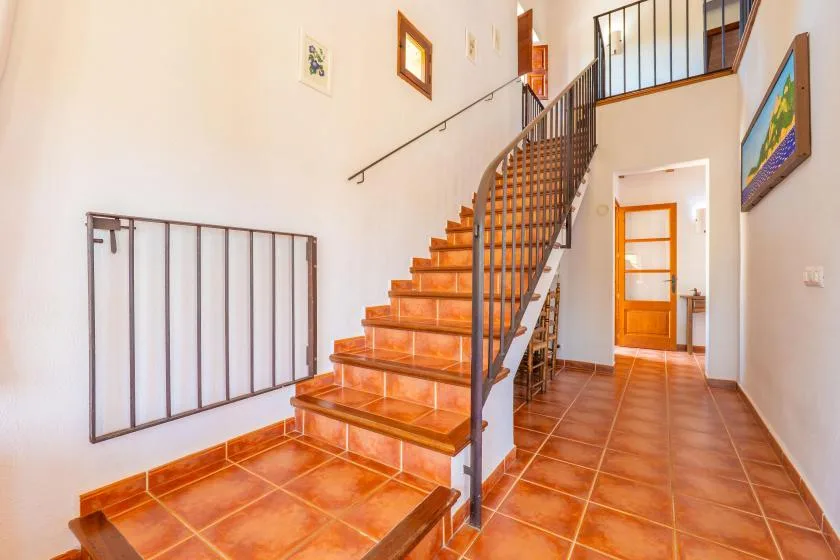 A tiled entry hall with a staircase and a wooden door.