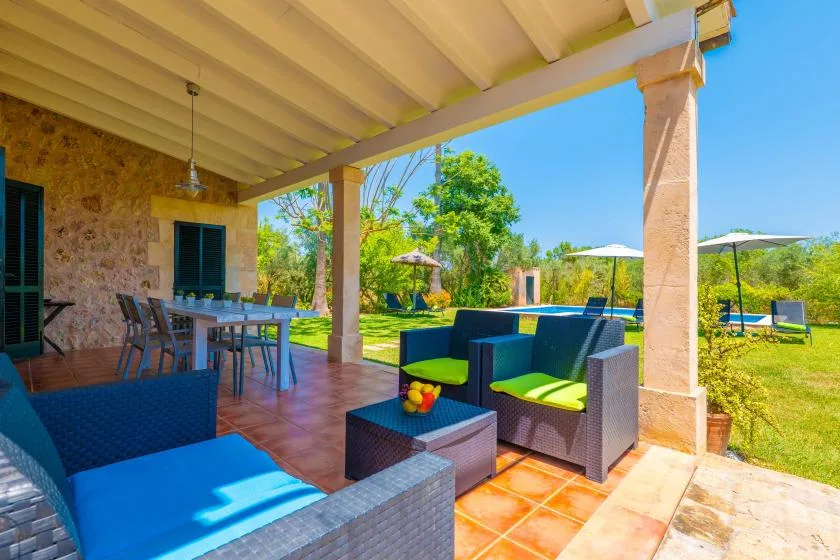 A covered outdoor patio with seating and a garden view.