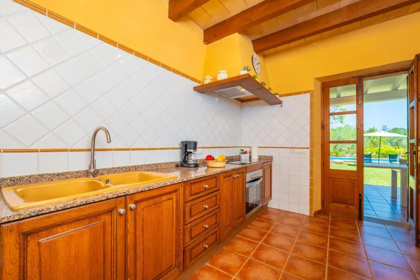 A kitchen with wooden cabinets and a countertop beside an open patio doorway.