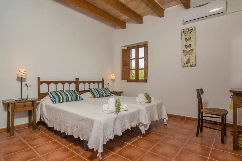 A bedroom with a double bed, bedside tables, and a window.