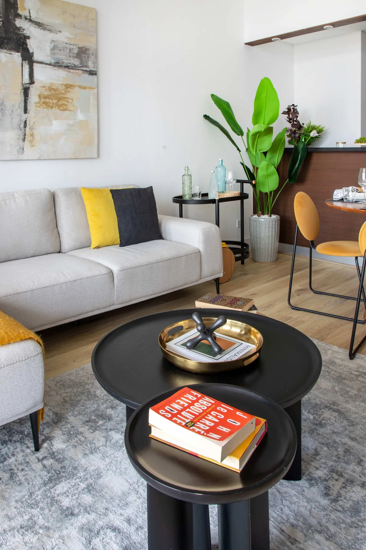 A living room with a light-colored sofa, round coffee tables, and a leafy plant.