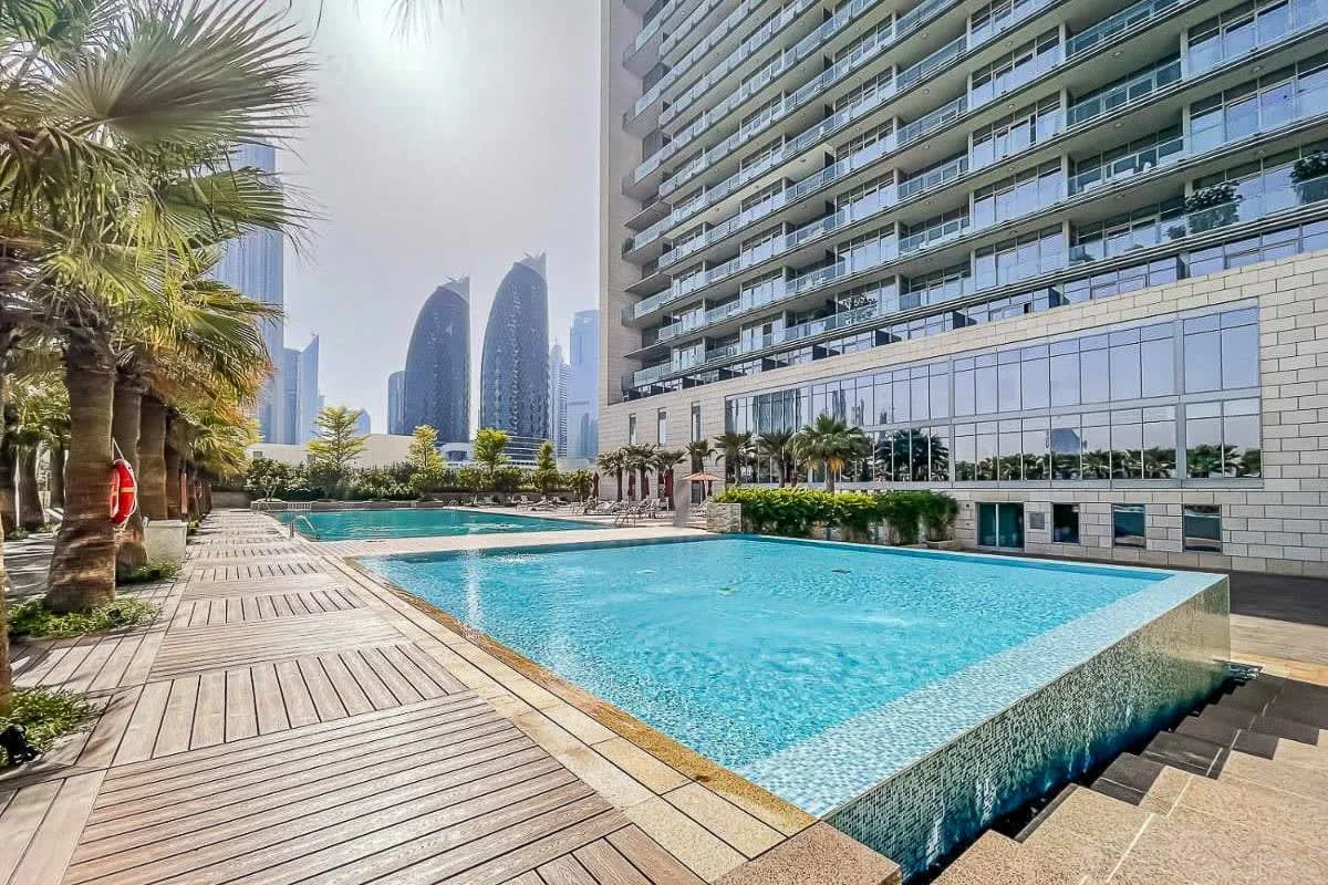 An outdoor swimming pool beside a modern high-rise building.