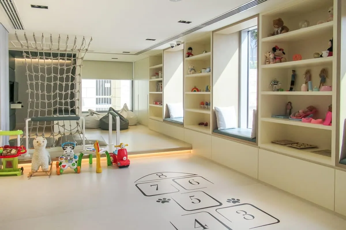 A bright playroom with built-in shelves, toys, and a hopscotch pattern on the floor.