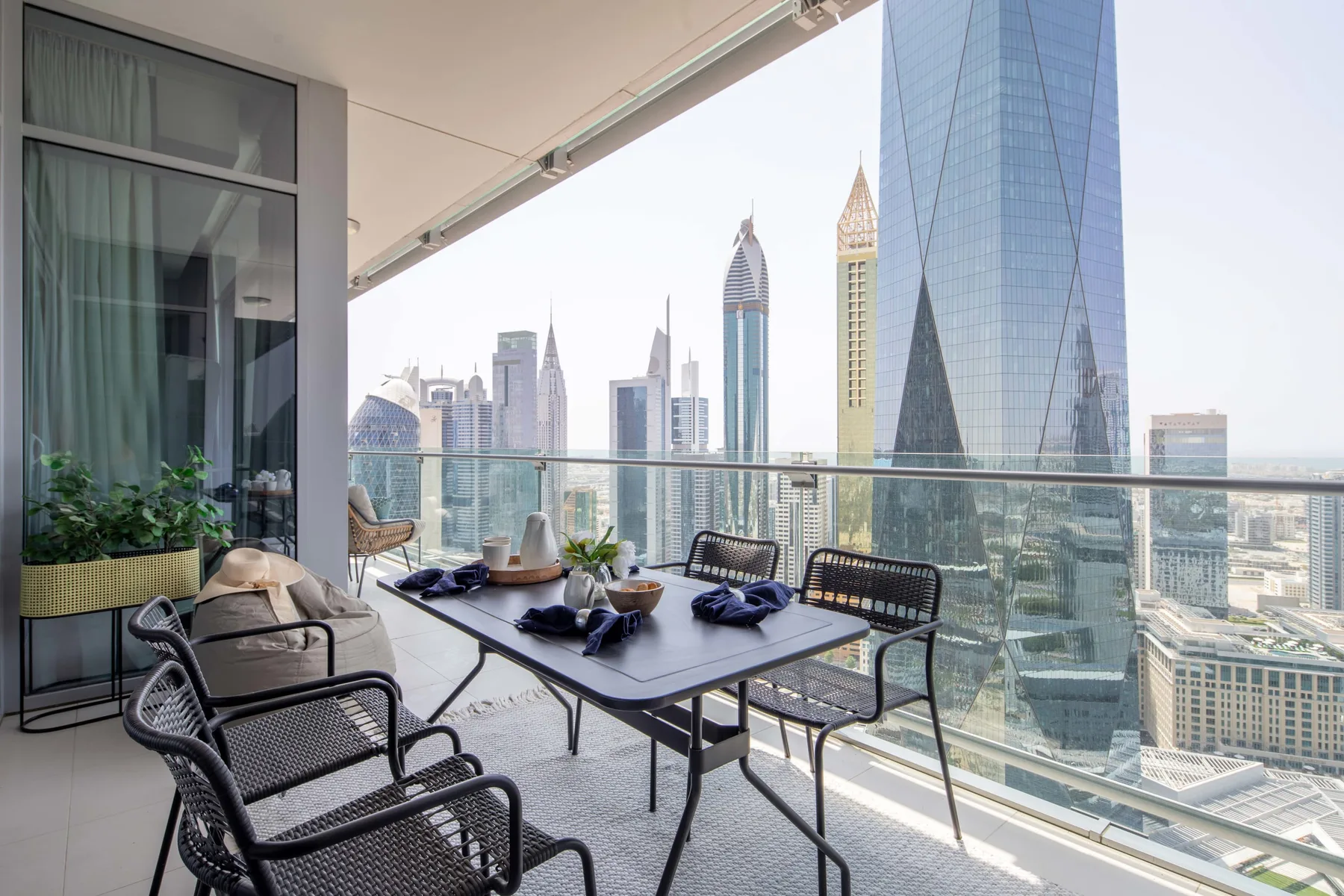 A balcony seating area with a table overlooks a city skyline.