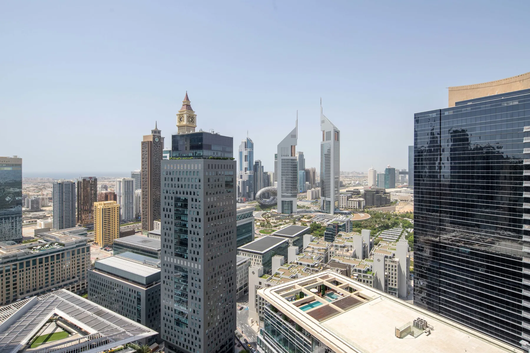 A city skyline viewed from above, with modern high-rise buildings under a clear sky.