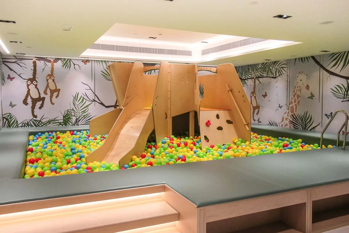 An indoor play area with wooden slides and a colorful ball pit.