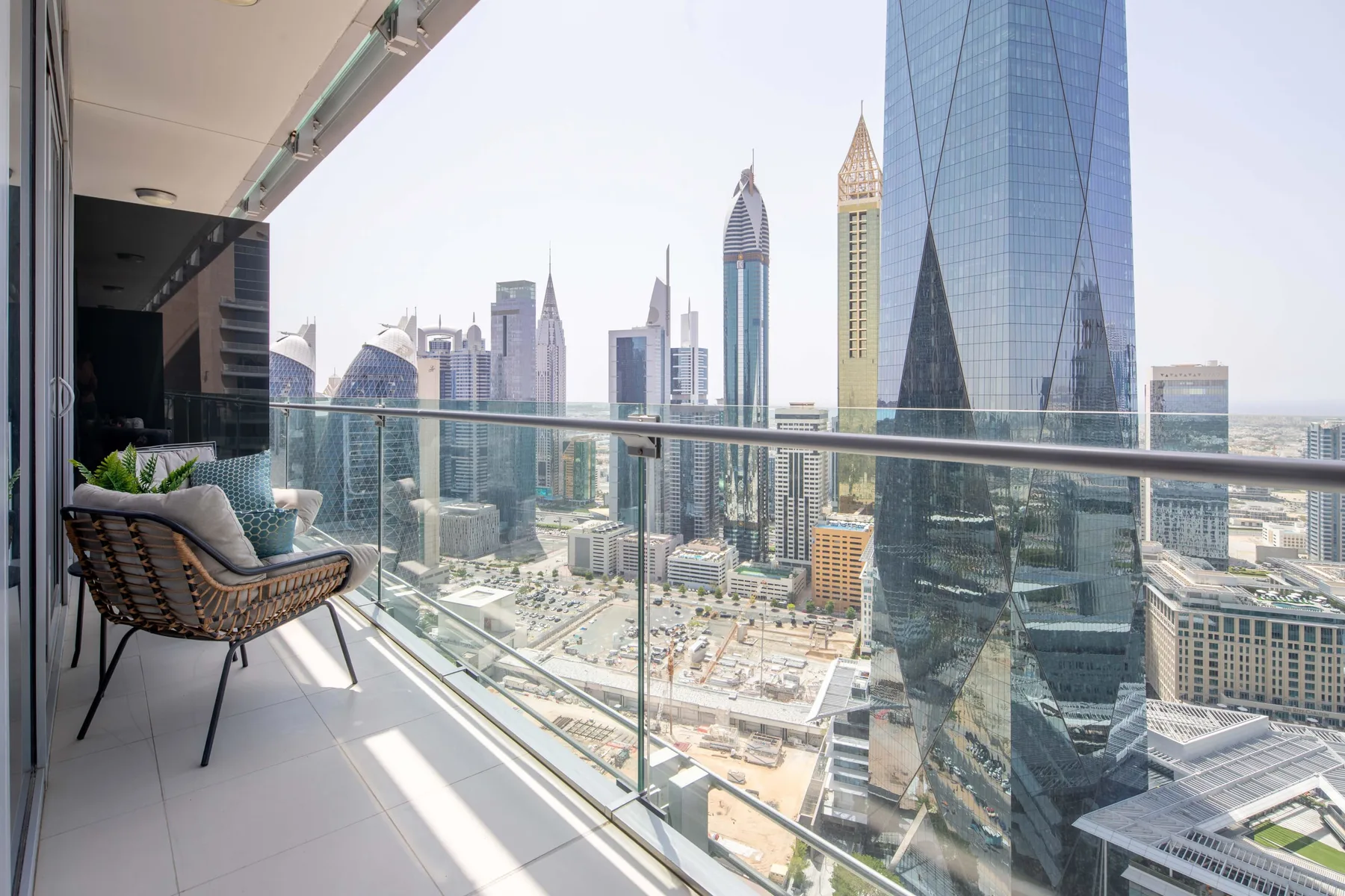 A balcony seating area overlooks a city skyline through a glass railing.