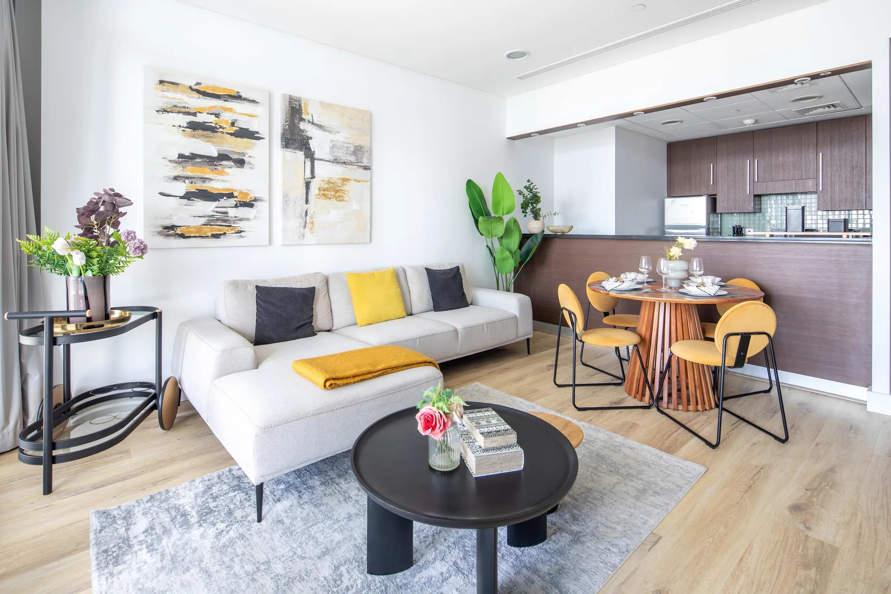 Una luminosa sala de estar y comedor con asientos, una mesa de centro y cocina.